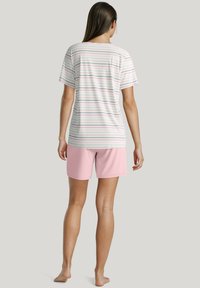 Gestreept T-shirt met korte mouwen in lichte kleuren, gecombineerd met roze shorts. Het shirt heeft meerdere dunne strepen in blauw, roze en wit.