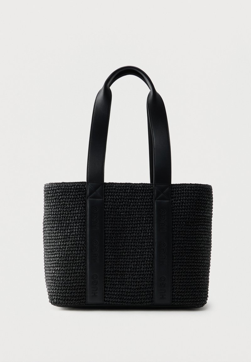 Μαύρη υφασμάτινη τσάντα ώμου με δύο φαρδιές δερμάτινες λαβές και διακριτική ανάγλυφη σήμανση στις λουρίδες των λαβών, με φόντο απλό λευκό.