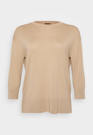 Bēšas adītas džemperis ar apaļu kakla izgriezumu, trīs ceturtdaļu piedurknēm un brīvu piegriezumu. Ribu malumi un apakša piešķir tekstūru izstrādājumam.