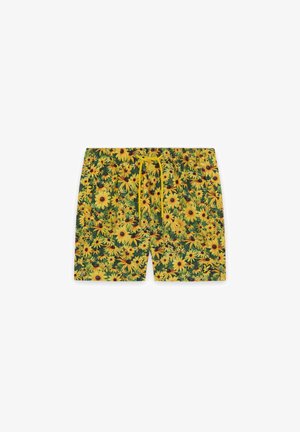 Shorts de bain pour hommes avec un motif de tournesols jaunes éclatants et un cordon de serrage jaune assorti sur un fond vert.