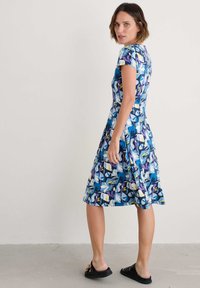 Lühikeste varrukatega sinine kleit lillemustriga, millel on valged, kollased ja lillad aktsendid, flirdiks volang seeliku ja siledast kangast tekstuur.