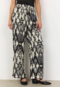 Pantaloni fluido con motivo in bianco e nero, dotati di vita elastica, caratterizzati da un dettaglio con fiocco e una vestibilità ampia, abbinati a ballerine nere.