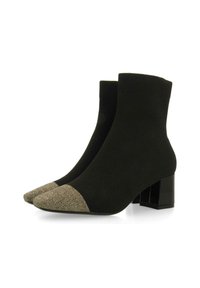 Botas negras hasta el tobillo con parte superior de punto, puntera con manchas doradas en contraste y un tacón negro grueso. Textura suave en todo el calzado.