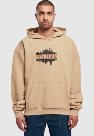 Beige hætte sweatshirt med en sort skyline grafik og teksten "NEW YORK" i rød, med en kængurulomme og ribbede manchetter.