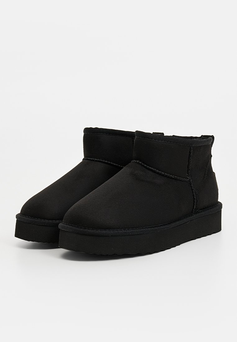 Schwarze Knöchelstiefel aus weichem Wildleder mit runder Spitze, minimaler Naht und einer strukturierten Sohle für besseren Halt.