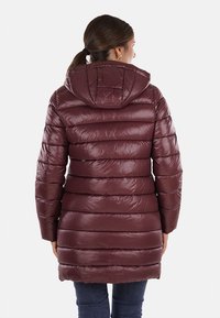 Cappotto imbottito bordeaux con cappuccio, caratterizzato da un design trapuntato, una texture lucida e dettagli di cuciture orizzontali, che arriva a metà coscia.