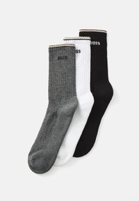 Three pairs of ribbed socks: one gray, one white, and one black. Each features a logo on the cuff and contrasting colored trims.