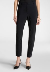 Pantaloni neri su misura con un design aderente, tessuto liscio e chiusura a bottone. Presentano una silhouette slim e una lunghezza cropped.