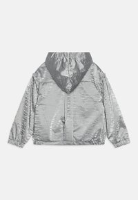 Srebrna metaliczna kurtka z kapturem, o błyszczącym, teksturowanym wykończeniu, z elastycznymi mankietami i luźnym krojem. Posiada ściągany kaptur i minimalistyczne detale.