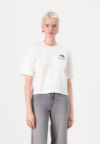 Hvit cropped t-skjorte laget av bomull, med korte ermer og et grafisk trykk av en fugl og teksten "BLAZING" på brystet.