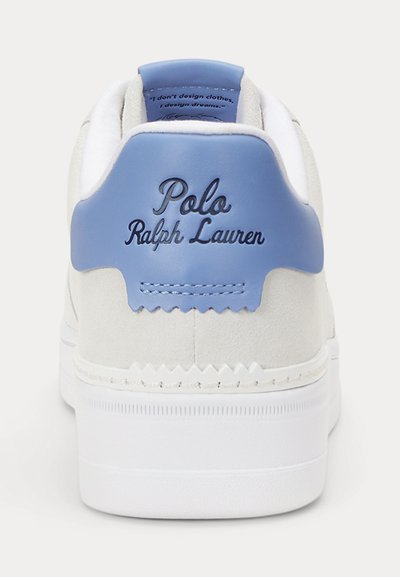 Bela superga s svetlo modrim jezičkom na peti, na katerem je vgravirana črna pisava logotipa "Polo Ralph Lauren". Vidna je gladka tekstura usnja in semiša.