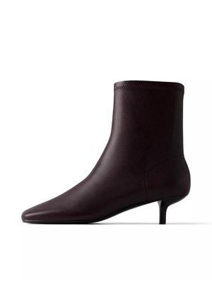 Bottine en cuir marron foncé avec bout pointu et petit talon kitten sur fond blanc.