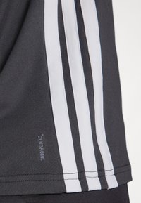 Črna športna majica z belimi vertikalnimi črtami ob straneh. Tkanina izgleda gladko, na robu je oznaka z napisom "climacool".