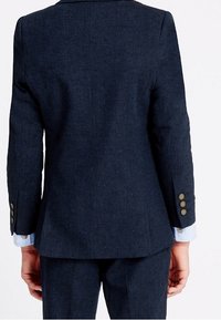 Granatowa marynarka dopasowana z teksturowanej tkaniny, o dopasowanym kroju, z jednym rozcięciem z tyłu i czterema złotymi guzikami na rękawach.