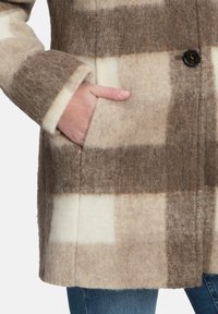 Wollmantel mit kariertem Muster in Braun und Creme, mit Knopfverschluss und Seitentasche. Weicher, strukturiert Stoff.