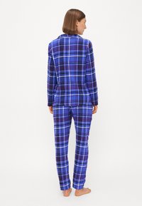 Ensemble de pyjama à carreaux dans des nuances de bleu et de violet. Haut à manches longues avec col, pantalon assorti, tissu doux et coupe décontractée.