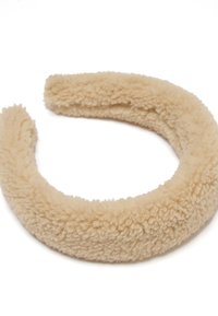 Cinta para la cabeza de felpa beige, diseño redondeado, textura suave, superficie aterciopelada, con un color uniforme y sin patrones o accesorios adicionales.