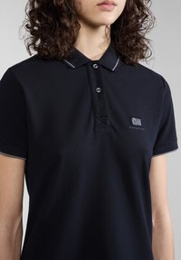 Námornícky polo triko s texturovanou látkou, s trojicí knoflíčků a kontrastními akcenty na límci. Malé logo na hrudi. Krátké rukávy.