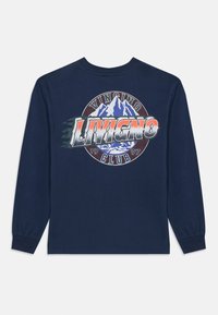 Mornarska majica dugih rukava s velikim grafičkim otiskom planina i natpisom "Livigno Club 1997" u kontrastnim bojama. Mekani pamučni materijal.