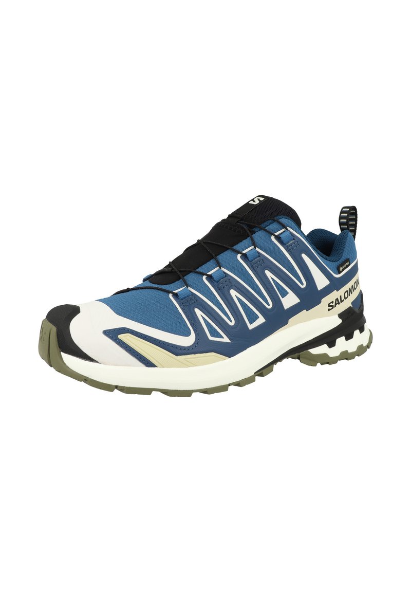 Chaussure de sport bleue avec un dessus en tissu texturé, accents noirs et une semelle blanche contrastante. Dispose de lacets élastiques et d'une languette de traction.