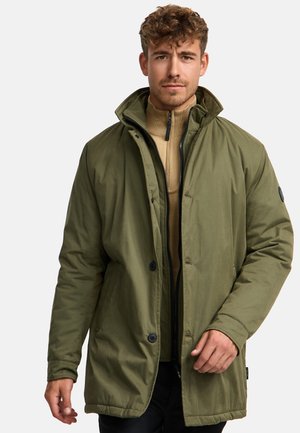 Olive green, long, insulated jacket with a zip and button closure, featuring a stand collar and smooth texture. Black logo accent on sleeve.