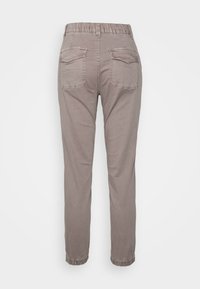 Calças beiges ajustadas com cintura elástica e bainhas dobradas. Apresentam dois bolsos traseiros e uma textura de tecido suave.