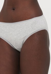 Grijze katoenen slip met delicate kantafwerking langs de tailleband en beenopeningen. Soepele textuur met een aansluitend ontwerp.