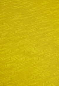 Tessuto lavorato a maglia giallo con un fine motivo a punto consistente e sottili variazioni di texture diagonali.