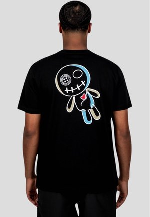Camiseta de algodón negra con un gráfico de una muñeca estilizada en la parte trasera, con acentos en azul, beige y rojo. Mangas cortas y corte holgado.
