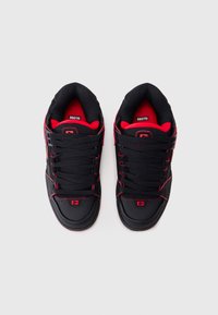 Black sneakers with red accents, featuring a smooth leather toe, textured mesh tongue, and thick black laces. Logo on tongue and side.