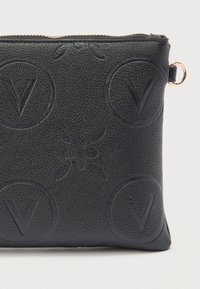 Musta teksturoitu nahkalompakko, jossa on kohokuvioidut pyöreät V-logot ja mehiläiskuvio, kultainen vetoketju ja metallisormus.