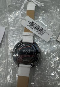 Ronde horloge van roestvrij staal met een witte leren band. Op de achterkant staan de tekst "regal", modelnummer 1072782 en een streepjescode-label.
