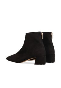 Botines de ante negro con puntera puntiaguda, tacón corto de bloque y cierre de cremallera en la parte trasera. Textura suave con detalles mínimos.