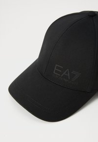Svart baseballcaps laget av glatt stoff, med et hevet EA7-logo foran og en klassisk buet brem.