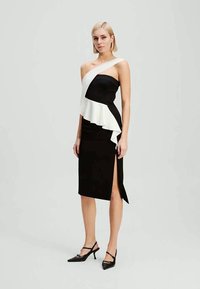 Μαύρο και άσπρο strapless φόρεμα με φουσκωτό ασύμμετρο σκέλος και πλευρική σχισμή. Κατασκευασμένο από λείο ύφασμα με εφαρμοστή σιλουέτα.