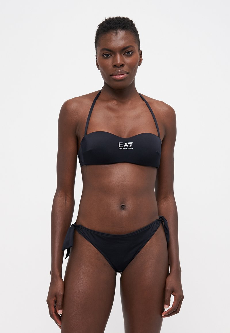 Svart bikini-sett laget av glatt stoff. Toppen har et bandeau-design med bånd, og bunnen har justerbare sidebånd. EA7-logoen er synlig.