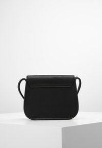 Černá kožená taška přes rameno s plochým, zaobleným tvarem, uzavíráním na předním klopě a tenkým, nastavitelným popruhem. Hladký povrch s minimálními detaily.
