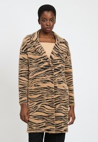 Lang, beige frakke med et sort tigerstribe-m�ønster, lavet af fuzzy materiale. Har en slagkrave og to forlommer.