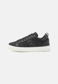 Black sneakers with a textured mesh and leather upper, round eyelet detail, black laces, and a white rubber sole.