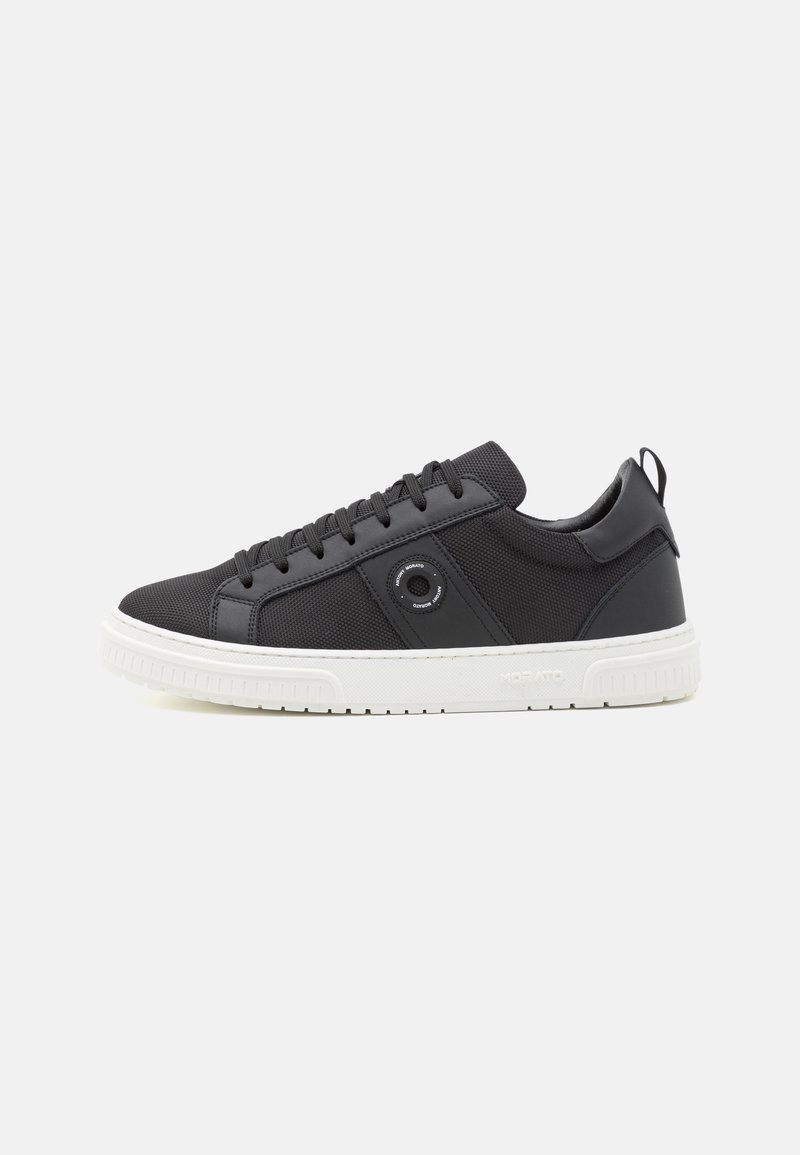 Black sneakers with a textured mesh and leather upper, round eyelet detail, black laces, and a white rubber sole.
