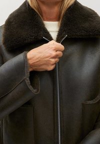 Brun læder zip-up jakke med en uldkrave, sidelommer og en glat tekstur med en afslappet pasform. Lynlåsen er central og metallic.