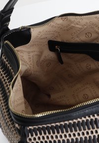 Vävd handväska med svart läderdetalj och gyllene dragkedja. Inuti har den en beige textil med präglad "CAFÉ NOIR"-logotyp.