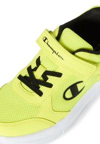 Neon żółty but sportowy z siateczkową cholewką, czarnymi sznurówkami i logiem Champion. Posiada rzep oraz białą gumową podeszwę.