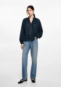 Mörkblå skjorta med knappar och en strukturerad mönster, kombinerad med ljusblå raka jeans och svarta loafers. Enkel och avslappnad design.