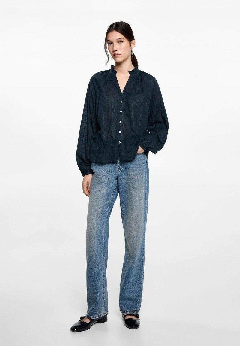 Mörkblå skjorta med knappar och en strukturerad mönster, kombinerad med ljusblå raka jeans och svarta loafers. Enkel och avslappnad design.