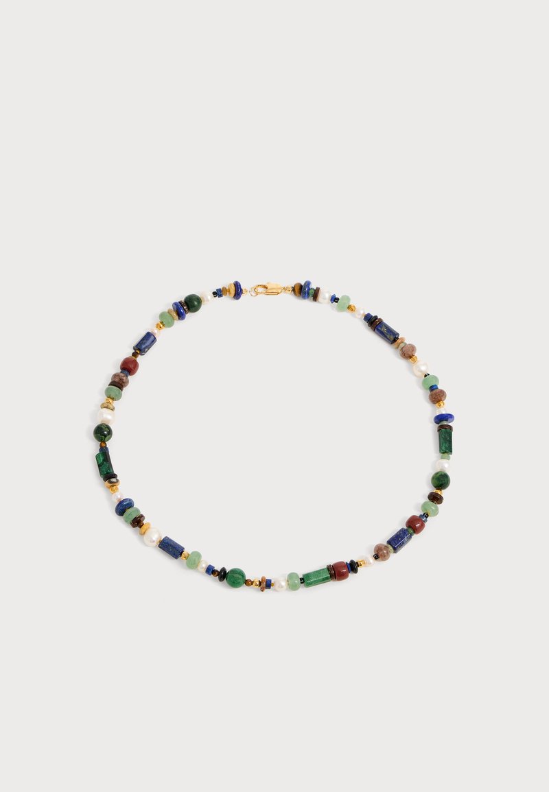 Collier de perles multicolores avec des perles vertes, bleues, rouges et dorées disposées en motif circulaire sur un fond clair.