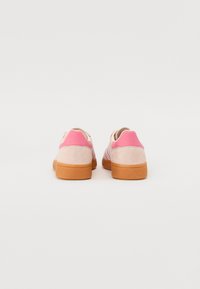 Sportssko med rosa overdel, laget av semsket skinn og mesh-materialer, og med såle av gummi. Har et stripete design og polstret krage for komfort.