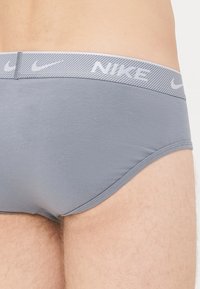 Graue Baumwollunterhose mit einem gemusterten, elastischen Bund, der das Nike-Logo trägt. Enganliegendes Design und glatte Textur, die die Form betont.