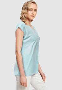 Lyseblå kortærmet t-shirt med V-hals, der har et diskret logo på brystet og en løs, afslappet pasform.