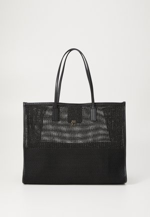 Black woven tote bag with long handles, featuring a mesh design at the top and a solid base, accented by a small gold logo.